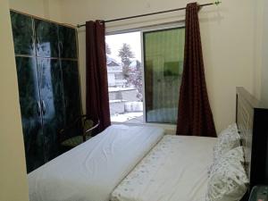a bedroom with a bed and a large window at Al Hussain Family Apartments in Murree