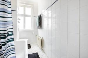 une salle de bain blanche avec toilettes et fenêtre dans l'établissement Zwei Charmante Privatzimmer mit Wohnbereich in zentraler Berliner Wohnung, à Berlin 38 autres photos