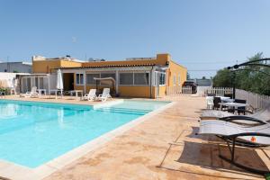 a swimming pool with chairs and a house at 10 e Lode in Mazara del Vallo