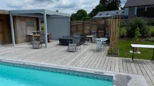 um pátio com uma mesa e cadeiras ao lado de uma piscina em B&B Les Autres Sens em Villers-la-Ville