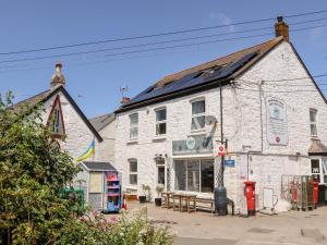 un edificio de piedra blanca con un banco delante en The Attic en Helston