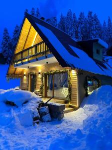 una cabaña de madera en la nieve por la noche en Hotel Te Liqeni en Peje