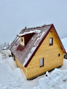 una casa in legno con neve sul tetto di Hotel Te Liqeni a Pejë