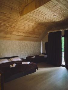a room with two beds and a wooden ceiling at Cottage Shina in Kazbegi
