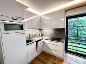 een witte keuken met witte kasten en een raam bij Premium Apartment Rokytnice in Rokytnice nad Jizerou
