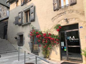 un edificio con flores rojas a un lado. en La Maison - Hôtel & Gîte en Laguiole