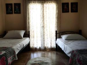 a bedroom with two beds and a window with curtains at Jenny's House in Yerakiní