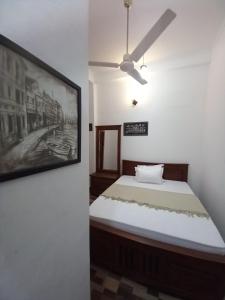 een slaapkamer met een bed en een schilderij aan de muur bij Villa Luxez in Kalmunaikudiyiruppu