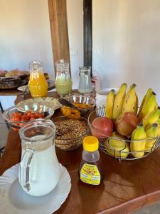 uma mesa com taças de fruta e um jarro de leite em Pousada/Camping Mirante Serrano em Alto Paraíso de Goiás