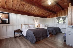 two beds in a bedroom with wooden ceilings and wood floors at Old Orchard Inn in Wolfville