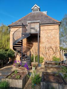 a brick building with a spiral staircase in a garden at Square Oast Studio in West Malling