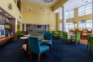 a waiting room with tables and chairs and a fireplace at Hampton Inn & Suites Jacksonville Deerwood Park in Jacksonville