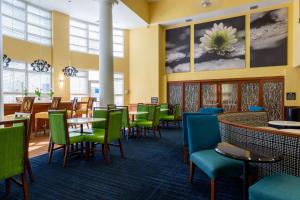 Hampton Inn & Suites Jacksonville Deerwood Park في جاكسونفيل: غرفة طعام مع كراسي وطاولات خضراء