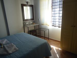 Schlafzimmer mit einem Bett, einem Spiegel und einem Fenster in der Unterkunft Kois Studios in Azolimnos