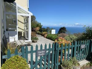 a house with a green fence with a garden studio sign at North Walk House in Lynton