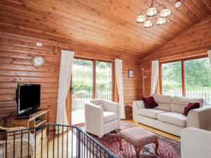 a living room with a couch and a tv at Dailfearn Chalet in Stromeferry