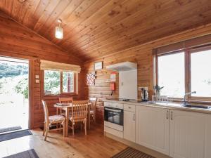 a kitchen and dining room with a table in a cabin at Dailfearn Chalet in Stromeferry