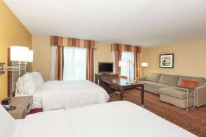 a hotel room with two beds and a couch at Hampton Inn & Suites Jacksonville-Airport in Jacksonville