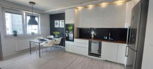 a kitchen with white cabinets and a table and chairs at Apartament Przymorze in Gdańsk
