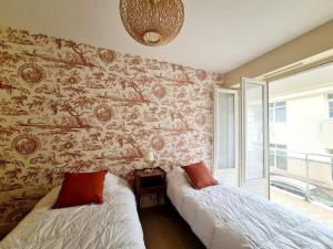 a bedroom with two beds in front of a wall at Appartement spacieux centre ville et plage à pied in Concarneau