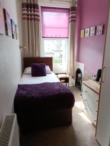 a bedroom with a bed with a purple blanket and a window at Lawnswood Guest House in Torquay