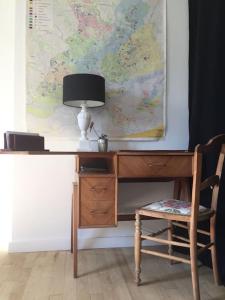a desk with a lamp and a chair next to a map at La petite maison et ses quatre vélos in Rezé