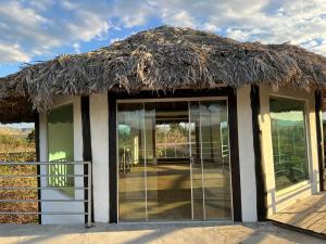 uma cabana com telhado de palha e portas de vidro em Pousada/Camping Mirante Serrano em Alto Paraíso de Goiás