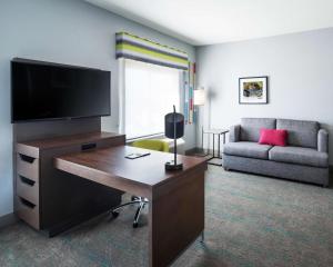 ein Wohnzimmer mit einem Schreibtisch, einem TV und einem Sofa in der Unterkunft Hampton Inn & Suites Lubbock in Lubbock