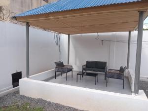 un patio con sillas y un techo azul en KADIDJA APARTMENTS & SUITES Hedzranawoe, en Lomé