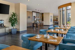 a restaurant with wooden tables and blue chairs at Hilton Garden Inn Los Angeles/Redondo Beach in Redondo Beach