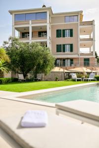 a house with a swimming pool in front of a building at Villa Hresc M in Zadar