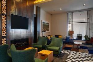 a living room with a fireplace and green chairs at Hampton Inn & Suites Sherman Oaks in Sherman Oaks