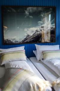 オンダルスネスにあるHotel Aakの白い枕2つと絵画が備わるベッドルーム1室