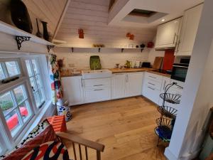 a kitchen with white cabinets and a wooden floor at Square Oast Studio in West Malling