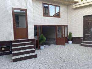 ein Haus mit einer Tür und einer Veranda mit Topfpflanzen in der Unterkunft Guest house Zebiniso in Samarkand