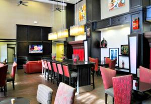 un restaurante con un bar con sillas rojas en Hampton Inn & Suites Bay City en Bay City