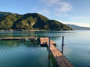 a dock on a lake with mountains in the background at Owase Seaside View in Owase