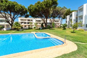 a swimming pool in front of a building at Host Wise - Amazing Sunny Flat - Swimming Pool & Terrace in Vilamoura