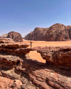 a person standing on a cliff in the desert at Wadi rum Rozana camp in Wadi Rum