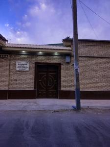 un edificio de ladrillo con una puerta con un cartel. en Guest house Zebiniso, en Samarkand