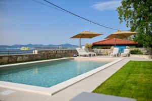 a swimming pool with two chairs and umbrellas at Villa Hrešć S in Zadar