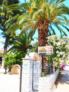 トロにあるVilla Christinaの椰子の木とホテルの看板