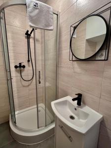 a bathroom with a shower and a sink and a mirror at Familly Apartament 6 in Międzyzdroje