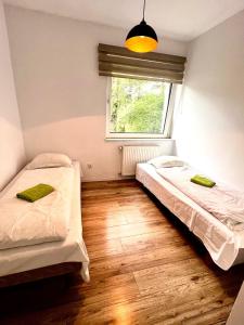 two beds in a room with a window and wooden floors at Familly Apartament 6 in Międzyzdroje