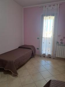 een slaapkamer met 2 bedden, een raam en een tegelvloer bij Appartamento Giulia in Muravera