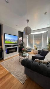 Stylish home close to Arena في Wincobank: غرفة معيشة مع أريكة وتلفزيون بشاشة مسطحة