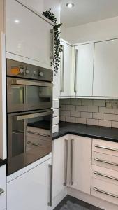 una cocina con armarios blancos y electrodomésticos de acero inoxidable en Stylish home close to Arena, en Wincobank