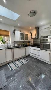 a large kitchen with white cabinets and stainless steel appliances at Stylish home close to Arena in Wincobank