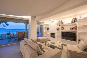 a living room with a couch and a tv at Villa Tholos -Athens Riviera in Kalívia Thorikoú