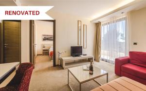 a living room with a red couch and a tv at Hotel & Apartments HEC Residence in Sveti Stefan